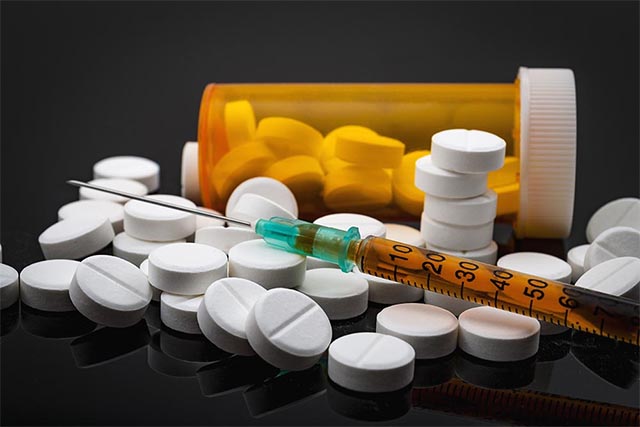 Close up photo of several addictive prescription drugs on a table with a pill bottle.