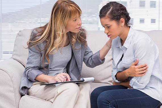 Therapist comforts woman receiving care for addiction and mental illness.