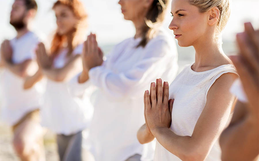 A group practices mindfulness for addiction recovery at an Orange County, CA beach.