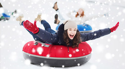 A woman enjoys sober fun during the holidays by inner tubing down a snowy hill.