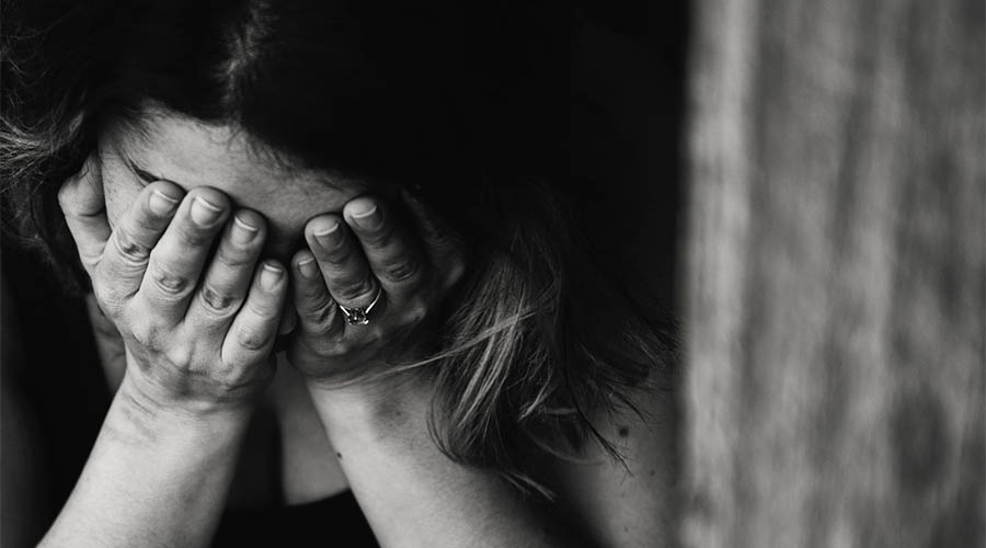 A person in recovery with their hands over their face, suffering from stress.