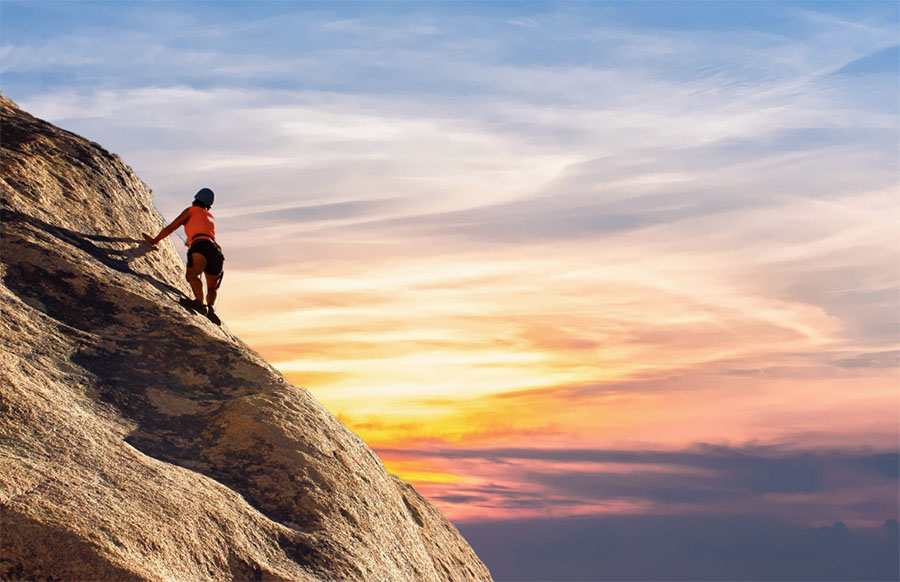 A person ascends a tall peak while climbing, a good contrast to recovery, which requires effort and work.