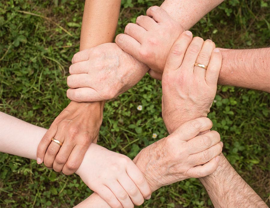 A group links their arms in a circle - showing a close bond in recovery, and a support system to prevent relapses.