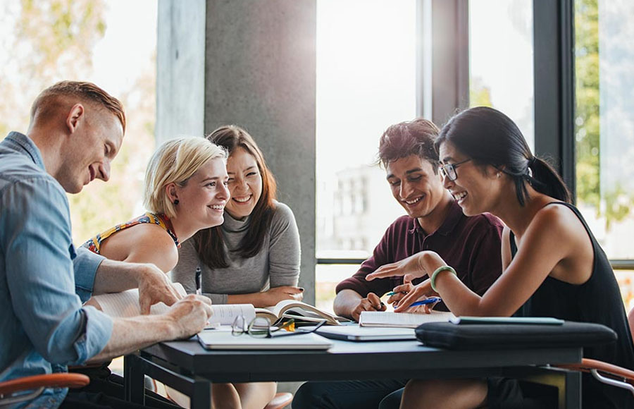 Sober students in college sit around a table talking.