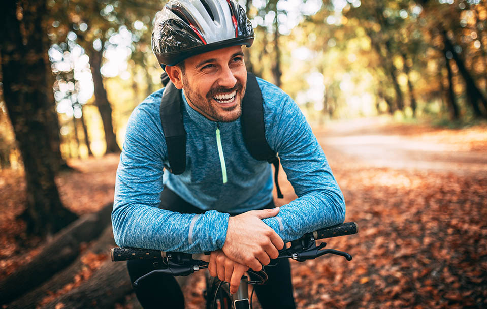 A man smiles from happiness as he mountain bikes through the woods, a popular sober hobby.