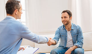 A man shakes hands with and meets his counselor after arriving at an Outpatient Treatment Center.