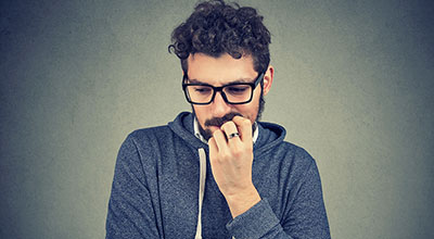 A man struggles with cravings in early recovery, putting his hand up to his face in frustration.