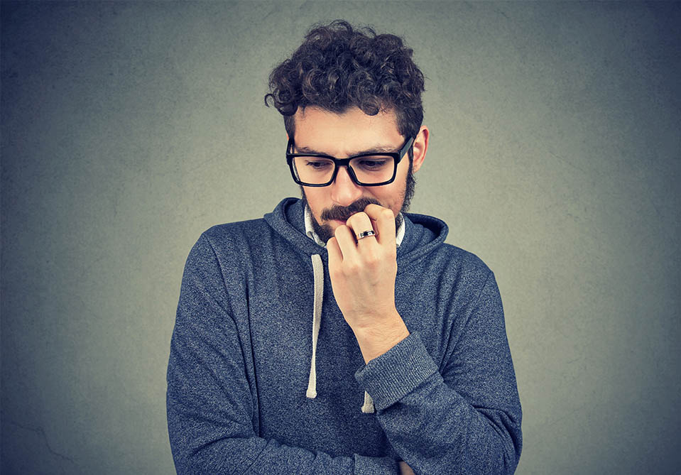 A man struggles with cravings in early recovery, putting his hand up to his face in frustration.