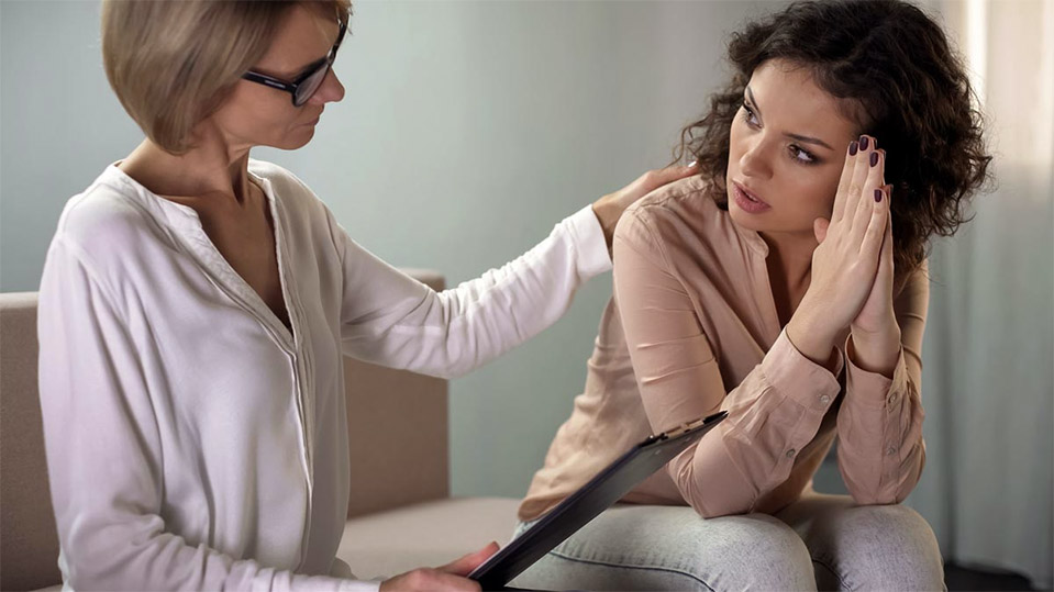 A woman is comforted by her therapist while in an addiction rehab that uses evidence-based care and treatment.