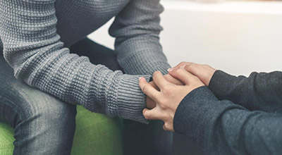 A gay man holds hands with his partner as he arrives at a rehab center.