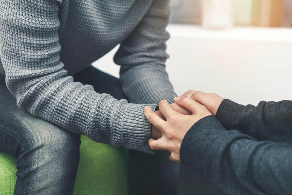 A gay man holds hands with his partner as he arrives at a rehab center.