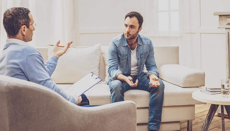 A man sits with his counselor discussing some of the long term side effects of his marijuana usage.