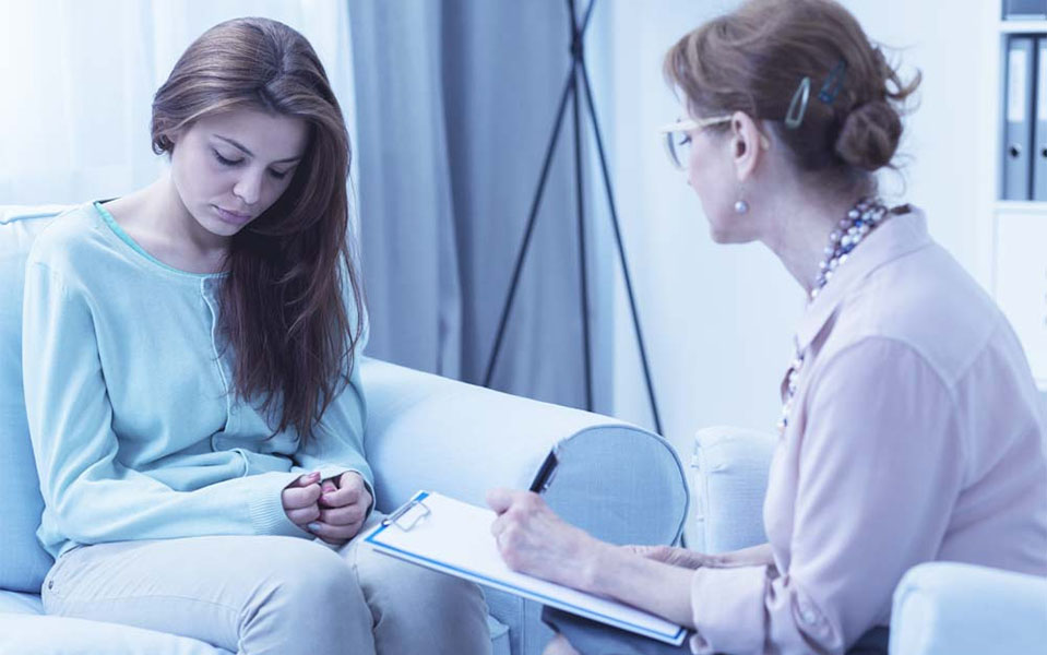 A woman suffering from depression and other symptoms is comforted by her therapist in rehab.