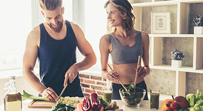 A woman and man make healthy food together, playing an important role in their sobriety and recovery from drugs and alcohol.