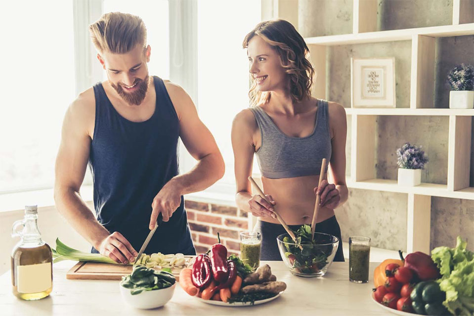 A woman and man make healthy food together, playing an important role in their sobriety and recovery from drugs and alcohol.