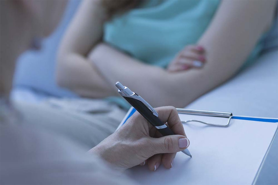 A doctor sits with a patient who has a nutritional deficiency, a common symptom of long term drug or alcohol users.