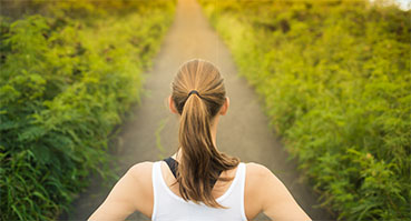 A woman looks down a long path contemplating - symbolizing the decision to get help for drug and alcohol addiction.