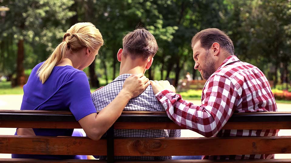 A mother and father comfort their son during a discussion about the role genetics play in the predisposition to addiction, and signs of an addictive personality.