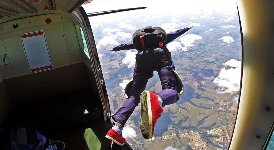 A man jumps out of a plane skydiving, a common activity for some thrill-seekers.