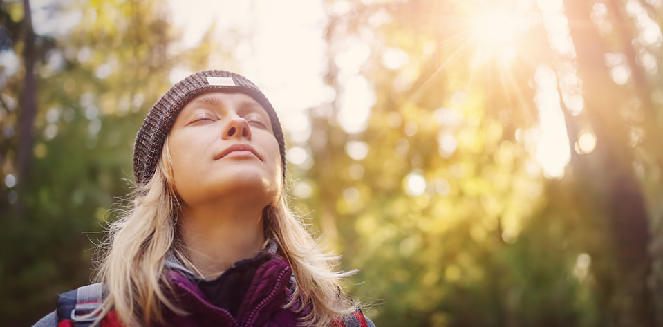 A woman breathes deeply, imagining herself outside in the forest. Using deep breathing to help with stress.