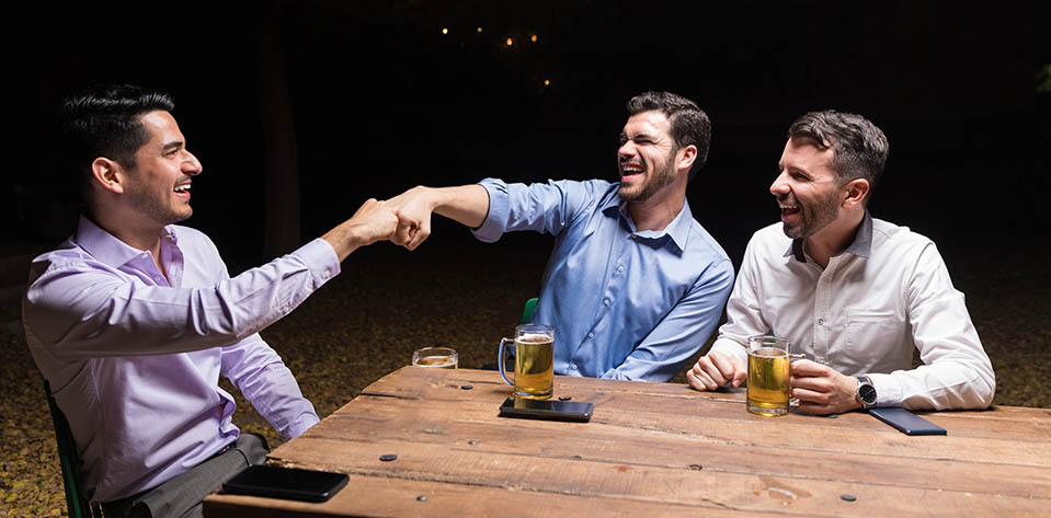 A man in recovery from alcoholism smiles and says goodbye to his friends who are drinking beer.