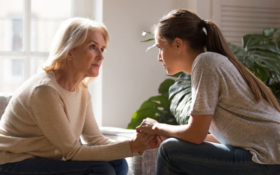 A mother and daughter hold hands and embrace after working through issues in a professional therapy session as part of a drug treatment program.