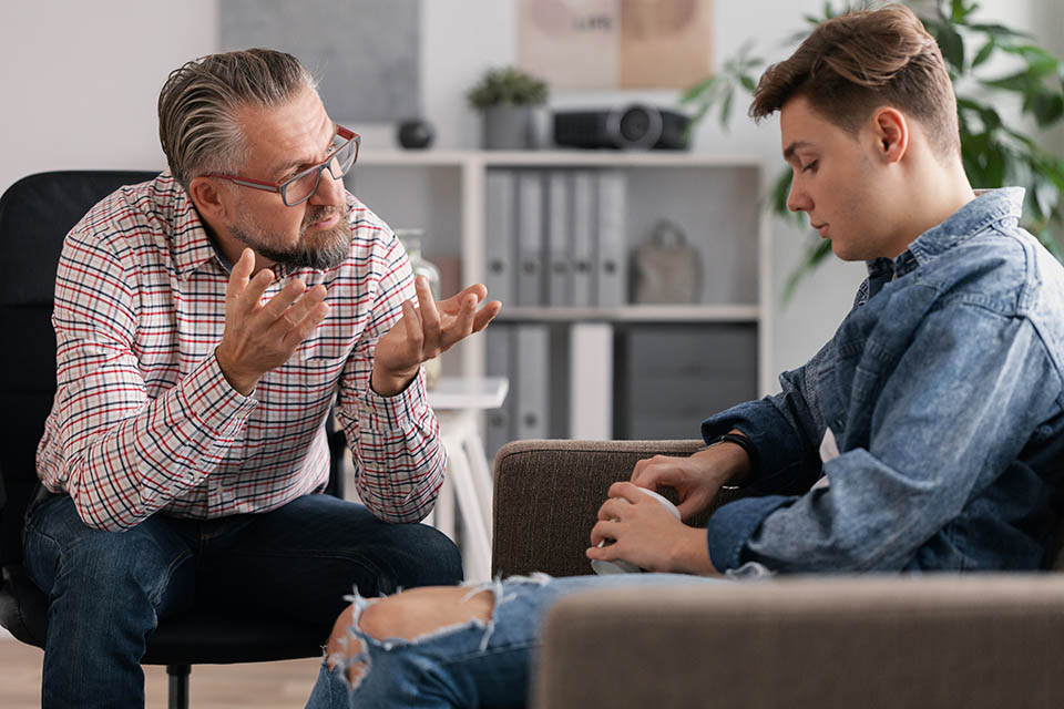 Signs of Addiction - A client sits with a therapist utilizing DBT Therapy for treating his addiction and mental health.