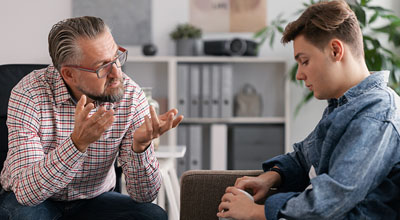 A client sits with a therapist utilizing DBT Therapy for treating his addiction and mental health.