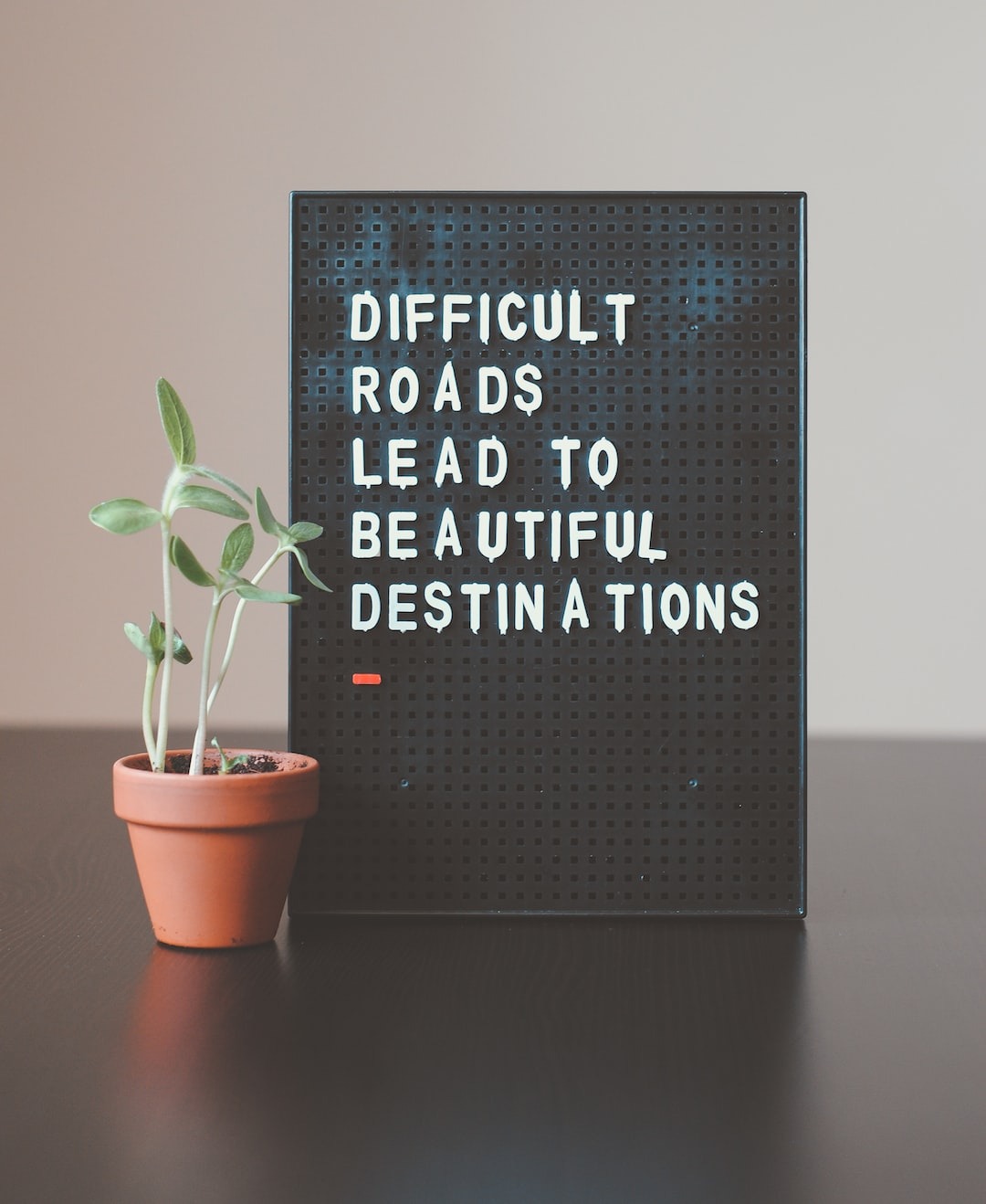 Motivational sign reading 'Difficult roads lead to beautiful destinations' next to a small potted plant, symbolizing growth and hope through Medication-Assisted Treatment (MAT).