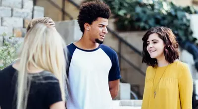 Young adults stand outside their outpatient treatment program chatting with each other.