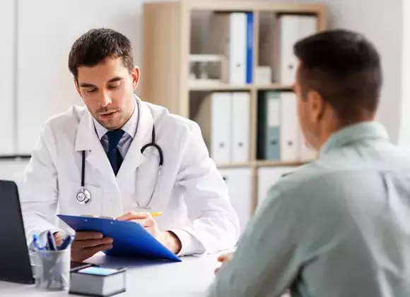 A young man sits across the desk from a doctor reviewing his chart shortly after entering a treatment facility to get help for his drug addiction and mental health problems.