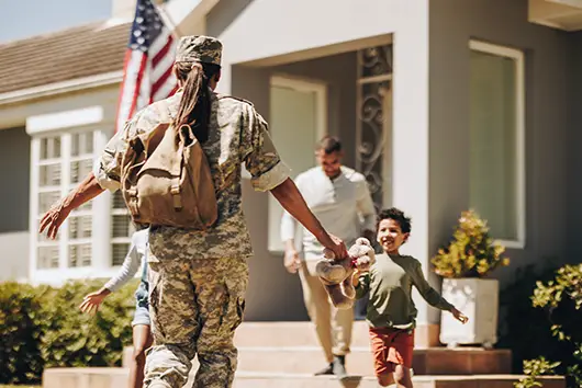 A member of the military returning home to their front steps to see their happy family