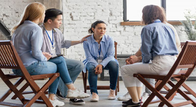Woman at group therapy talking about how she compares herself others while the group comforts her