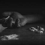 Hand hold laying on the table next to drugs