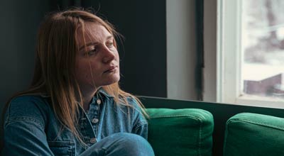 Woman looking outside a window suffering from bipolar disorder