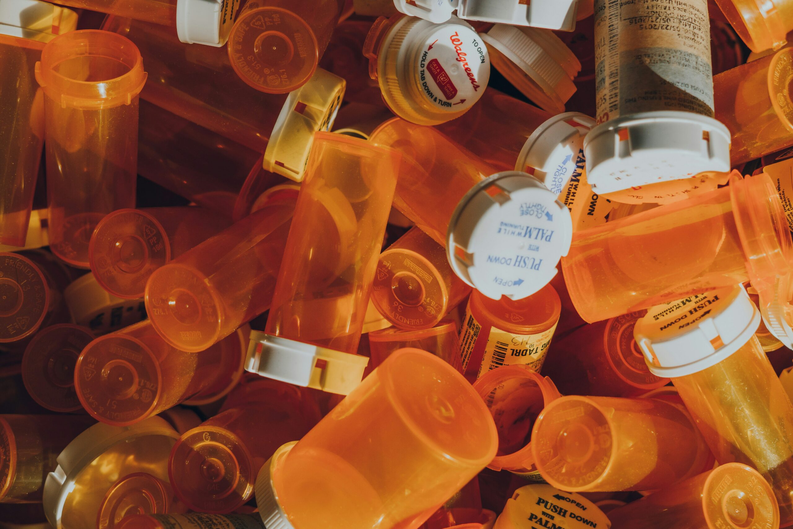 Many empty prescription medication bottles laid in a group empty