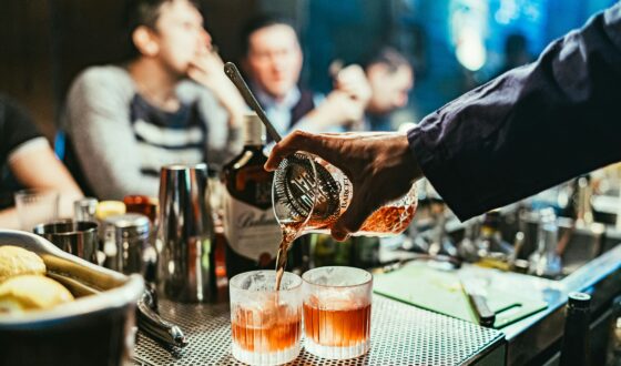 Shot of two whisky shots being poured on a bar top by a bar tender