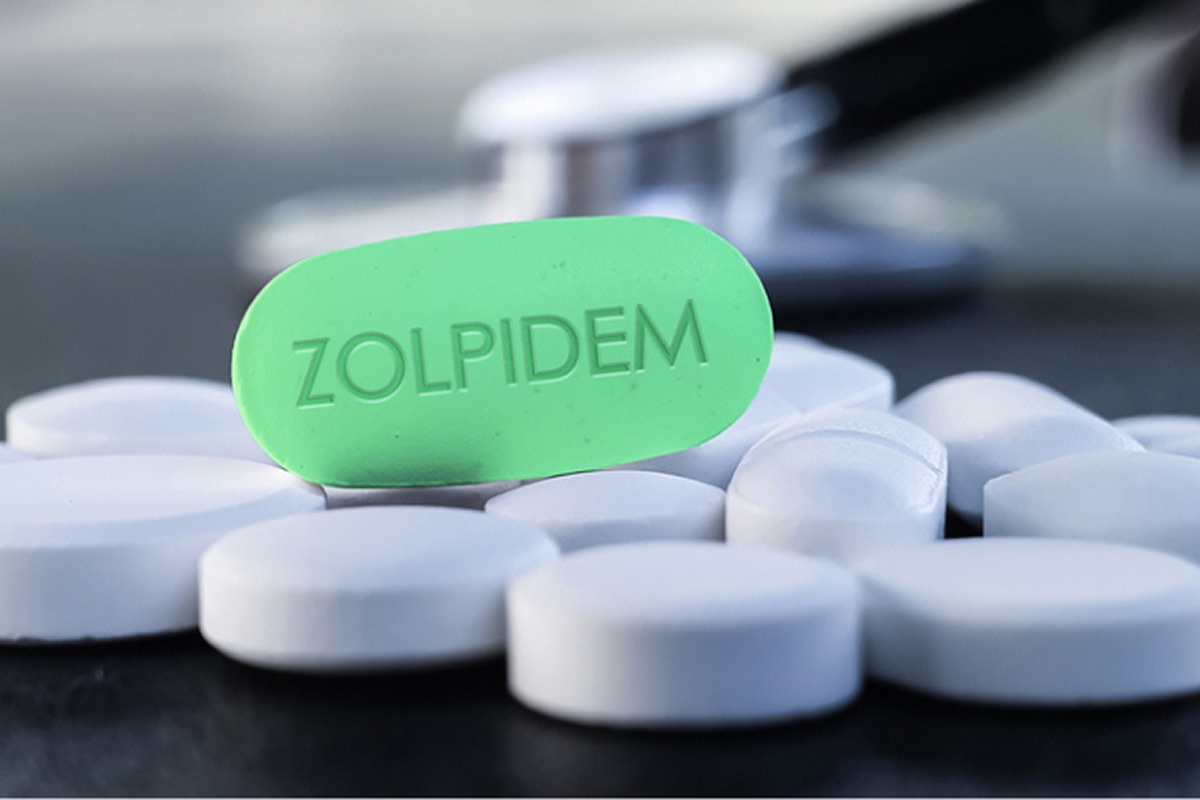 green Zolpidem pill sitting on a bunch of white pills symbolizing if Zolpidem is addictive