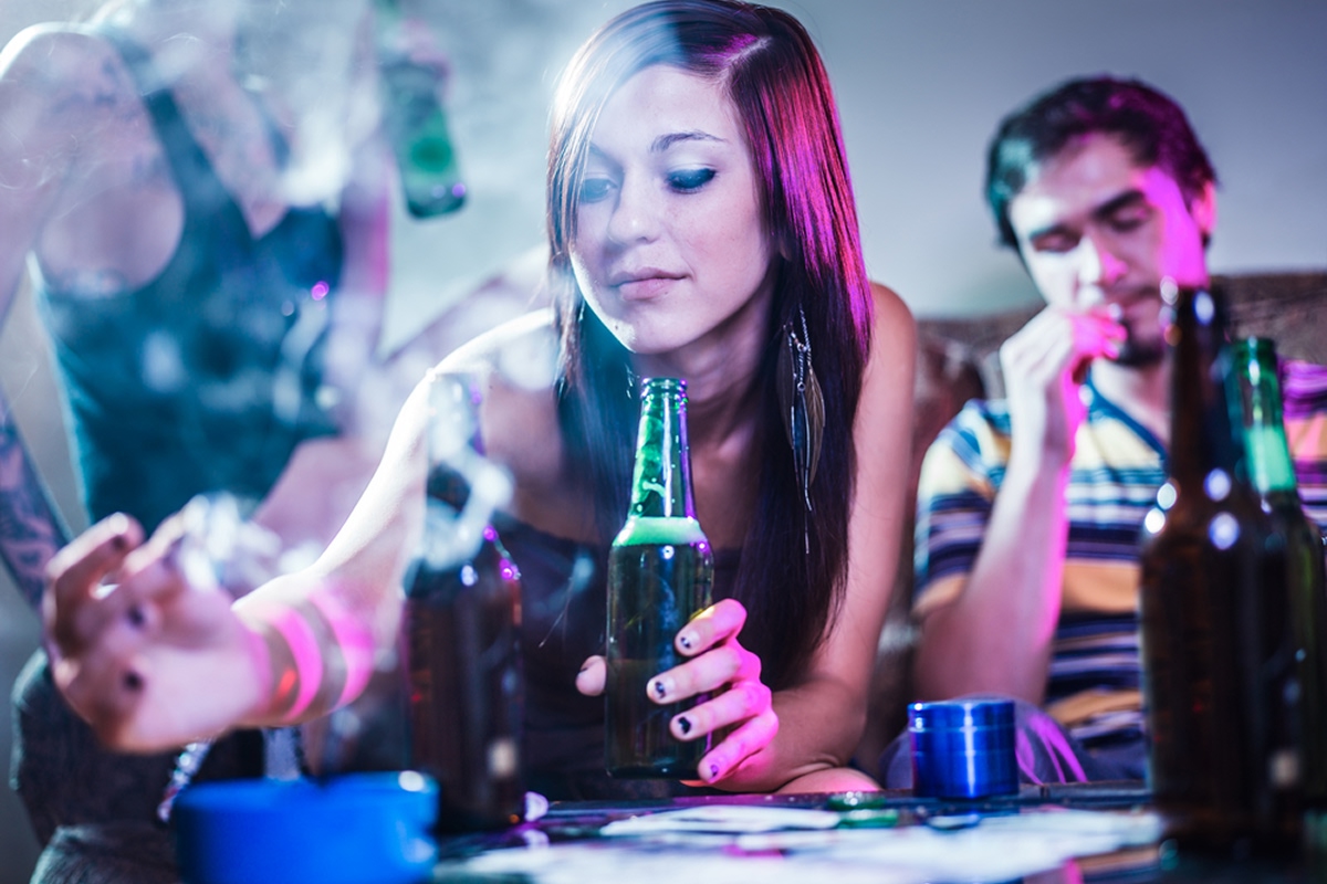 Young adults drinking alcohol and smoking in a party setting, illustrating the dangers of being cross-faded and experiencing blackouts — a focus of 12 South Recovery’s substance abuse education in Orange County, CA.