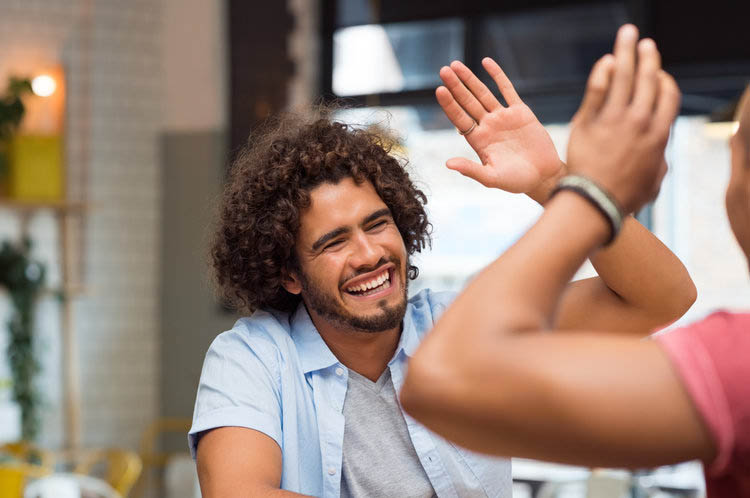Man smiling and celebrating progress with a high five, representing success in Orange County residential treatment and detox for addiction recovery.